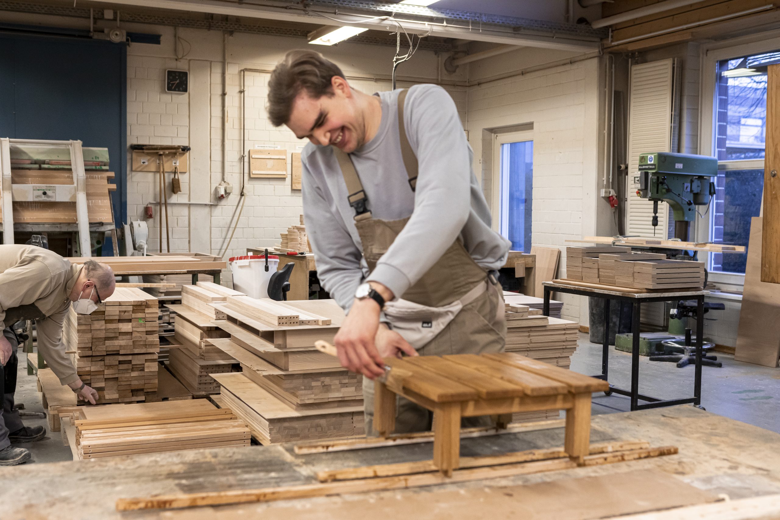 Mann streicht mit einem Pinsel einen Holztisch an